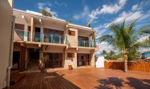 a house with a wooden deck and a palm tree at Anexo à Pousada WindJeri in Jericoacoara