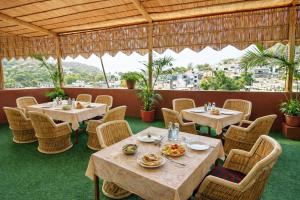a restaurant with tables and chairs and a view at Hotel Ashoka Mountabu in Mount Ābu