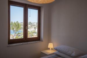 a bedroom with a window and a bed and a lamp at Villa Acquamarina, Family apartments with pool - 300 meters from the beach in Santa Maria +70 photos
