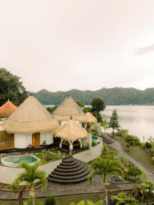 a resort with thatched huts and a body of water at Santhi Loka in Kubupenlokan