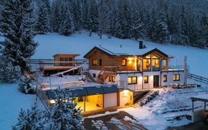 a house in the snow with lights on at Austrian Alpine Apartments in Ramsau am Dachstein