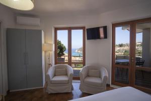 a bedroom with two chairs and a view of the ocean at Villa Acquamarina, Family apartments with pool - 300 meters from the beach in Santa Maria