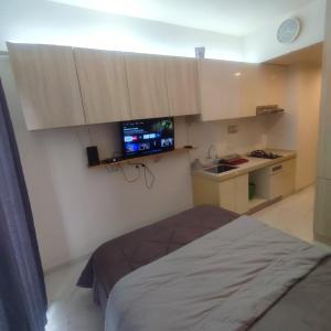 a room with a bed and a tv on the wall at Sky House BSD Apartment by Casanova in Cilenggang