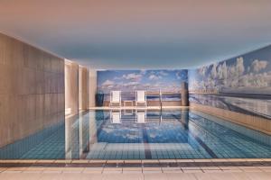 a swimming pool with two chairs and a painting on the wall at Hôtel Barrière Le Westminster in Le Touquet-Paris-Plage
