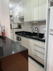 a kitchen with white cabinets and a black counter top at Energia Boa Estadia in Palhoça