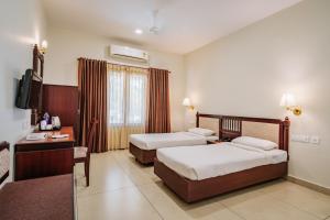 a hotel room with two beds and a television at Silver Crest Resort in Thekkady +26 photos