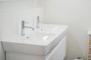 a white sink with two faucets in a bathroom at Downtown Zurich - Large, quiet private room "Alps" in homestay - Enge station - Lake & City - For 1 person in Zurich