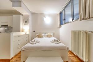 a white bedroom with a bed and a window at Sergio's house in Como