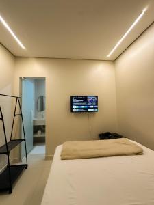 ein Schlafzimmer mit einem Bett und einem Flachbildfernseher an der Wand in der Unterkunft TERESINA HOTEL in Teresina