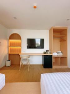 a bedroom with a desk and a tv on the wall at Wynora Hotel in Klong Toi