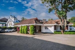 a white building with a tree in front of it at Silver Crest Resort in Thekkady