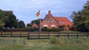 a house with a flag in front of a fence at Ballumerhoeve Skip lodge in Ballum +9 photos