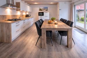 a kitchen with a wooden table and black chairs at Ballumerhoeve Skip lodge in Ballum