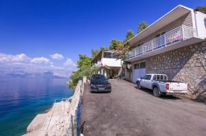 a car parked next to a house next to the water at Robinson Srdelica in Bogomolje