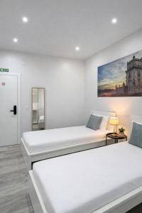 two beds in a white room with a painting on the wall at Velvet Prime Stay in Lisbon