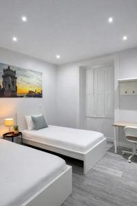 a white bedroom with two beds and a desk at Velvet Prime Stay in Lisbon