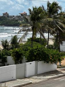 a white fence next to the beach with palm trees at Orla Pousada & Café in Parnamirim