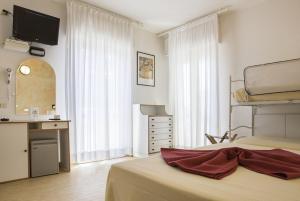 a bedroom with a bed with a dresser and a sink at Hotel Alba in Gabicce Mare