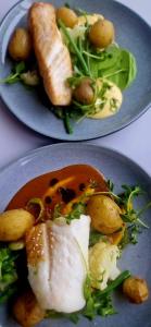two plates of food with meat and vegetables on them at Vardø Hotel by Destination Vardø in Vardø +42 photos
