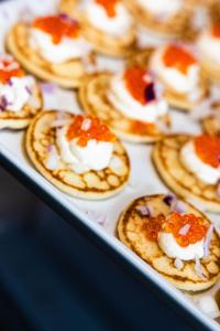 a tray of mini pizzas with sauce and cream at Vardø Hotel by Destination Vardø in Vardø