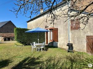a table and chairs with an umbrella in a yard at Le Refuge in Liernais