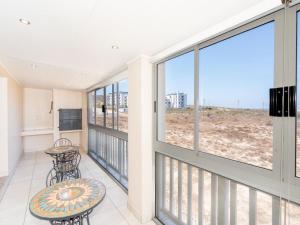 a balcony with a table and chairs and large windows at Sunset Heights in Langebaan +3 photos