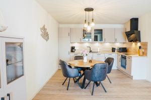 a kitchen with a wooden table and blue chairs at Küste33 34 in Tossens