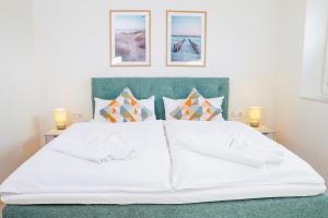 a bedroom with a white bed with three pictures on the wall at Küste33 34 in Tossens
