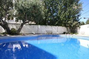 a blue swimming pool with trees and a white fence at Synergie SI14 - Sol Daurat in Cambrils