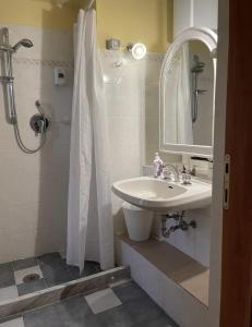 a white bathroom with a sink and a shower at Lo studio di Gabriella in Bolsena