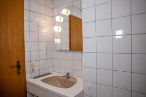 a white tiled bathroom with a sink and a mirror at Braugast Kreuz in Frastanz +16 photos