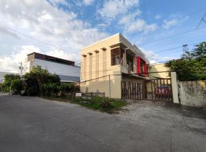 a white building with a red window on a street at SNOW Studio Apartment - Near Clark International Airport in Mabalacat