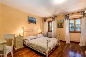 a bedroom with a bed and a desk and two windows at Il Palazzo in Volosko