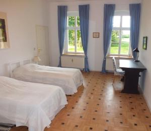 a bedroom with two beds and a desk and two windows at Rittergut Endorf in Endorf
