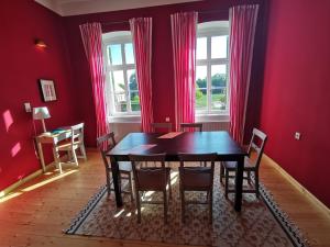 a dining room with a table and chairs and red walls at Rittergut Endorf in Endorf +15 photos