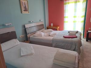 two beds in a room with red walls at Ground floor economy studio in karmiris studios in Zakynthos