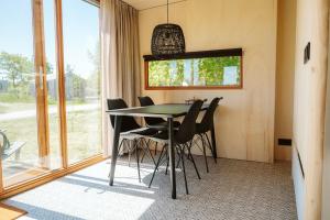 a dining room with a table and black chairs at Vakantiepark De Klepperstee in Ouddorp