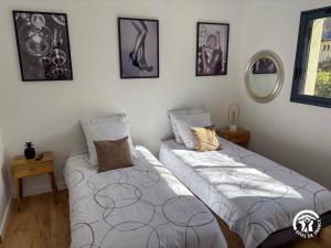 two beds in a room with pictures on the wall at Villa des Oliviers in Flavin