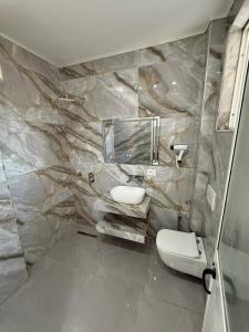 a bathroom with a marble wall with a sink and a toilet at ELIO's Room in Durrës