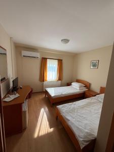 a hotel room with two beds and a desk at Popas Mara in Radna