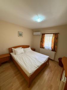 a bedroom with a bed with white sheets and a window at Popas Mara in Radna