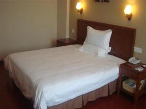 a bedroom with a white bed with a phone on it at GreenTree Inn Ji‘nan Shanda Road Business Hotel in Jinan