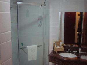 a bathroom with a glass shower with a sink at GreenTree Inn Ji‘nan Shanda Road Business Hotel in Jinan