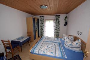 een slaapkamer met een bed, een tafel en een raam bij Plattnerhof in Kals am Großglockner