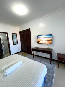 a white bedroom with a bed and a desk at The Initial Residence in Mombasa