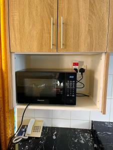 a microwave in a cupboard with a phone and a phone at The Initial Residence in Mombasa