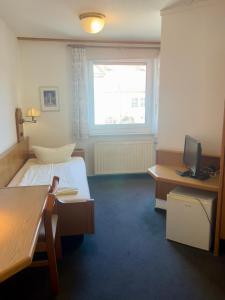 a room with two beds and a desk and a television at Hotel Feuerbacher Hof in Stuttgart
