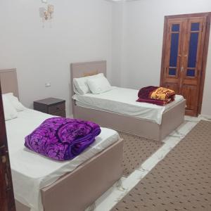 two beds in a room with purple blankets on them at Dakhly siwa in Siwa
