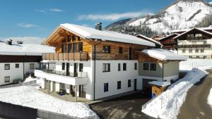 a building in the snow with a mountain in the background at Apart s'Peintl in Obertilliach