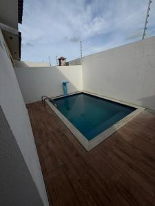 a swimming pool in a white room with a wooden floor at Casa de praia PB in Pitimbu